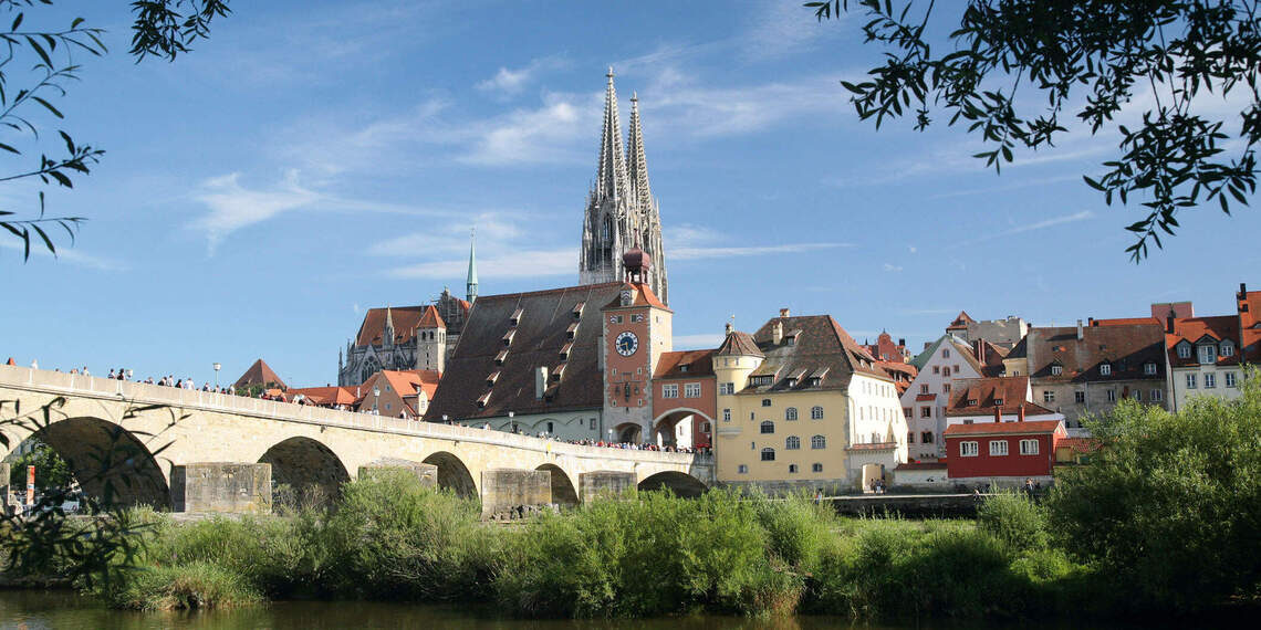 Eine malerische Steinbrücke überspannt den Fluss vor der Altstadt von Regensburg.